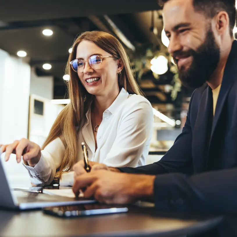 Kvinna och man med laptop i ett kontorslandskap.